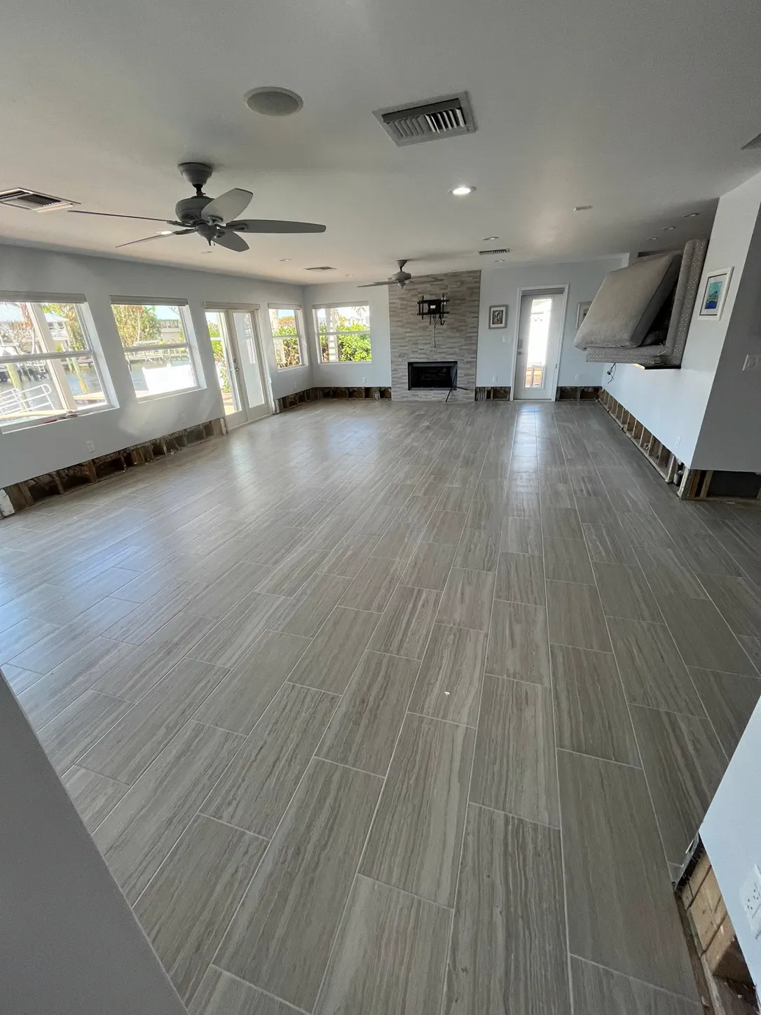 Newly installed gray wood-look porcelain plank floor across an open living room with water views